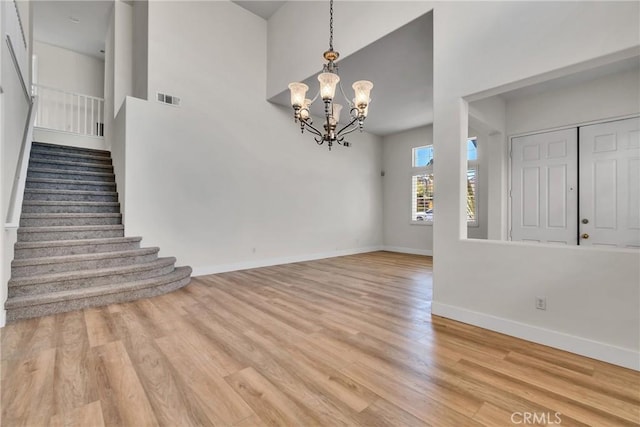 interior space featuring light hardwood / wood-style flooring, a high ceiling, and a notable chandelier