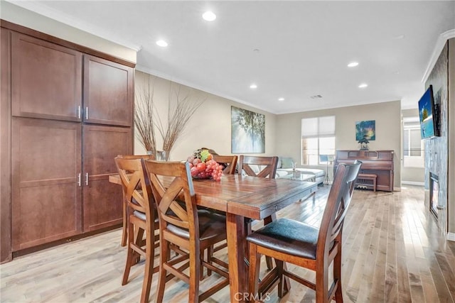 dining room with light wood-type flooring and crown molding