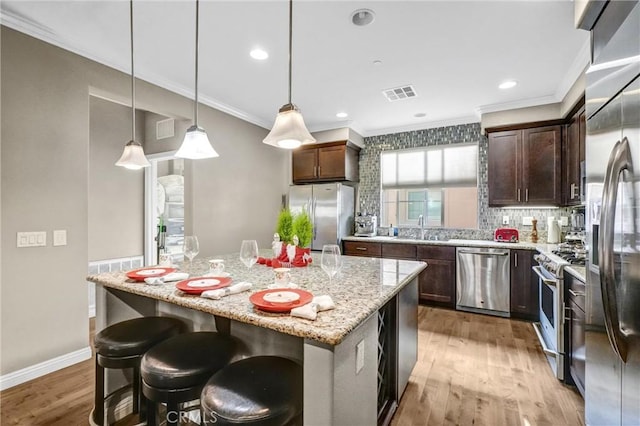 kitchen featuring pendant lighting, light hardwood / wood-style flooring, dark brown cabinets, a kitchen island, and stainless steel appliances