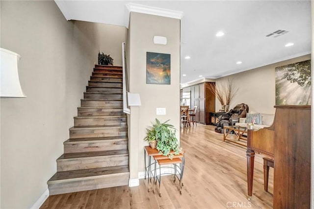 staircase with ornamental molding and hardwood / wood-style flooring