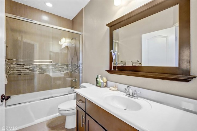 full bathroom featuring vanity, toilet, and shower / bath combination with glass door