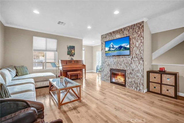 living room with light wood-type flooring, a fireplace, and ornamental molding