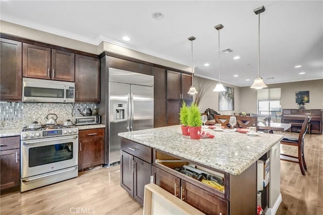 kitchen featuring pendant lighting, light hardwood / wood-style floors, light stone counters, and stainless steel appliances