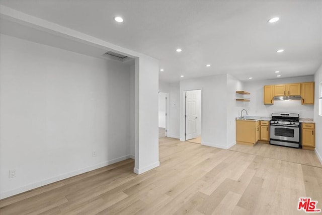 kitchen featuring stainless steel gas range oven, sink, light brown cabinets, and light hardwood / wood-style flooring