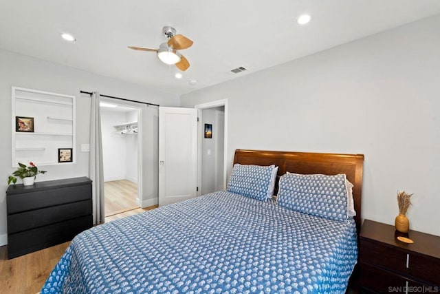 bedroom featuring hardwood / wood-style floors, ceiling fan, a spacious closet, and a closet