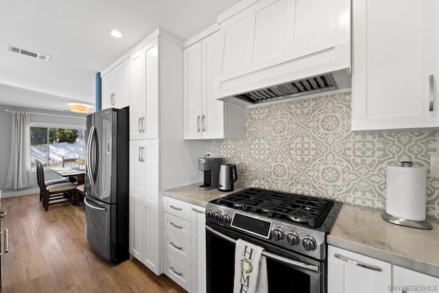 kitchen featuring light hardwood / wood-style floors, white cabinetry, custom range hood, and appliances with stainless steel finishes