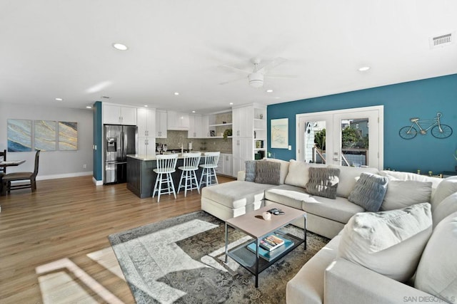 living room with hardwood / wood-style floors, ceiling fan, and french doors