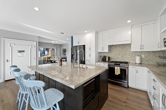 kitchen with sink, an island with sink, appliances with stainless steel finishes, and dark wood-type flooring