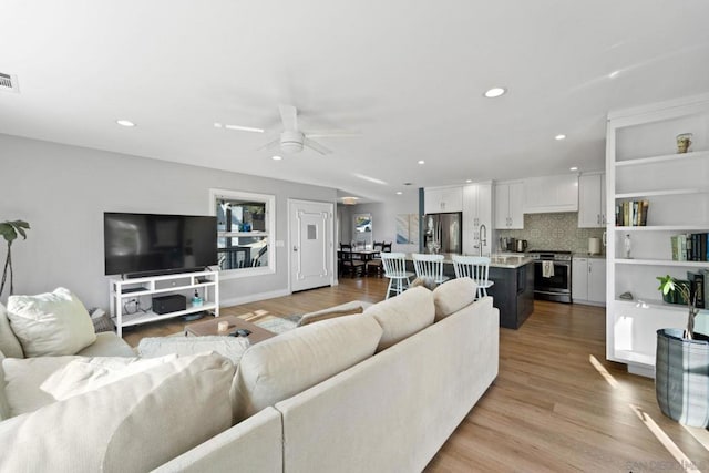 living room featuring ceiling fan, light hardwood / wood-style floors, and sink