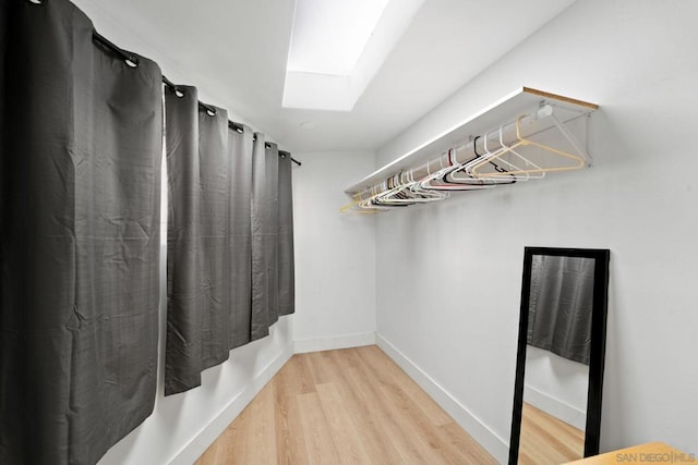 spacious closet featuring hardwood / wood-style flooring and a skylight