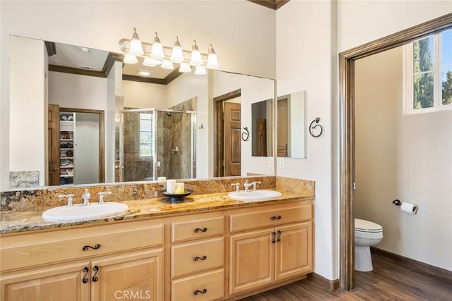 bathroom with hardwood / wood-style flooring, vanity, ornamental molding, a shower with shower door, and toilet