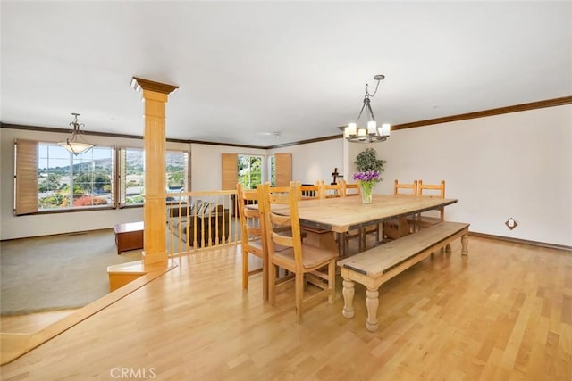 dining area with an inviting chandelier, ornamental molding, light hardwood / wood-style floors, and decorative columns