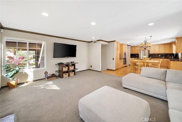 carpeted living room with ornamental molding, a chandelier, and sink