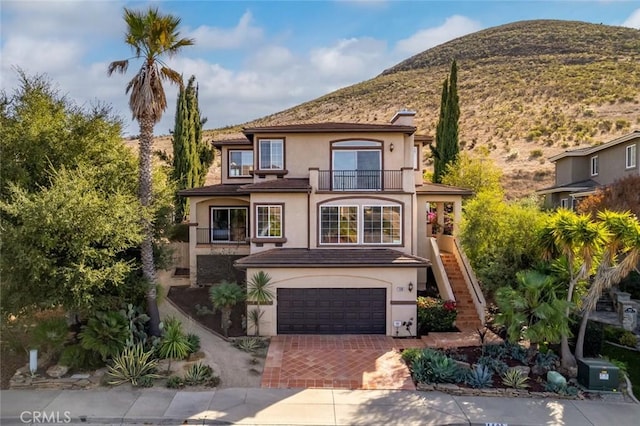 view of front of home with a garage, a balcony, and a mountain view