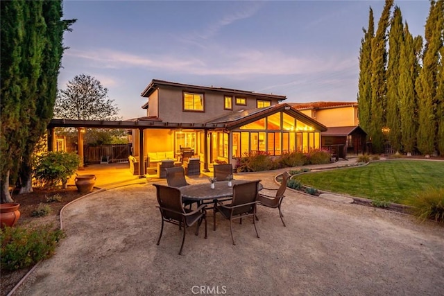 back house at dusk featuring a yard and a patio area