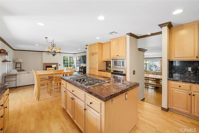 kitchen featuring a center island, light brown cabinets, pendant lighting, stainless steel appliances, and light hardwood / wood-style floors