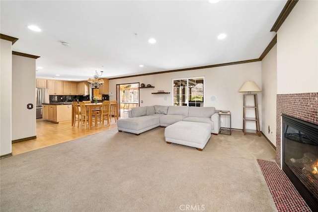 carpeted living room featuring crown molding, a tiled fireplace, and an inviting chandelier