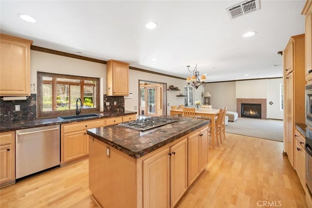 kitchen with sink, stainless steel appliances, a center island, and light brown cabinets