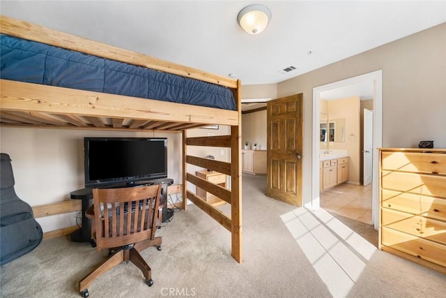 bedroom with light colored carpet and ensuite bath