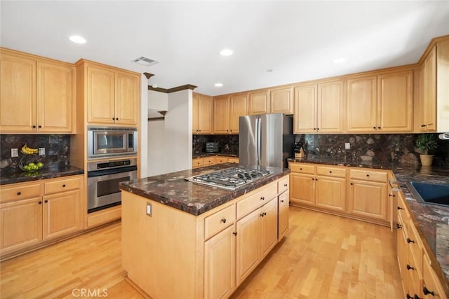 kitchen with backsplash, stainless steel appliances, a center island, light brown cabinetry, and light wood-type flooring