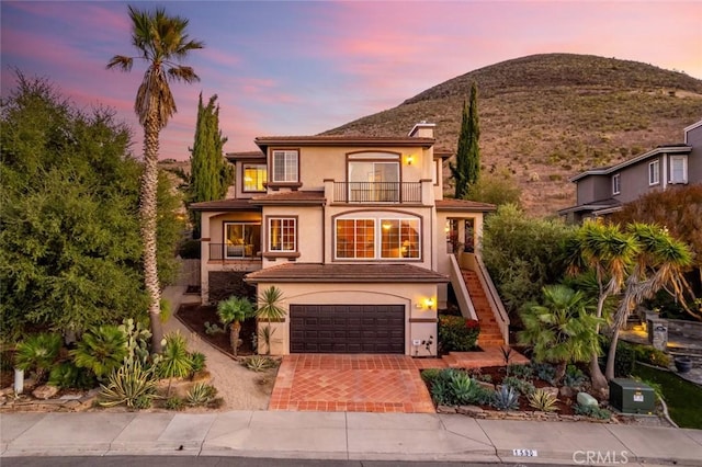 view of front of house with a balcony, a garage, and a mountain view