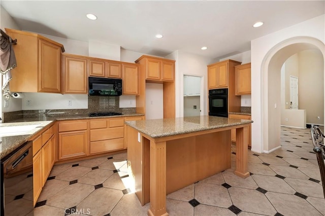 kitchen with sink, black appliances, light brown cabinets, stone counters, and a kitchen island