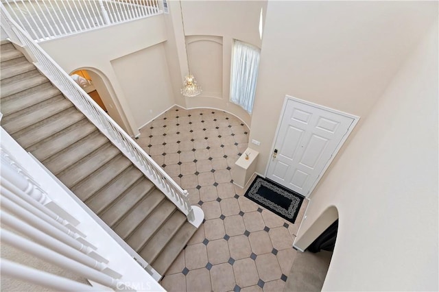 staircase with a towering ceiling and an inviting chandelier