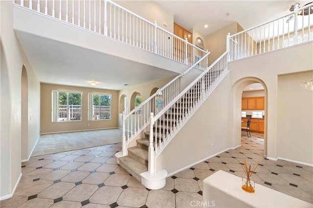 stairway with carpet and a towering ceiling