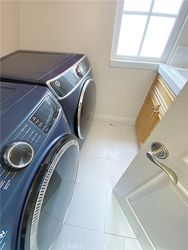 laundry room with baseboards, tile patterned floors, cabinet space, and washer and dryer