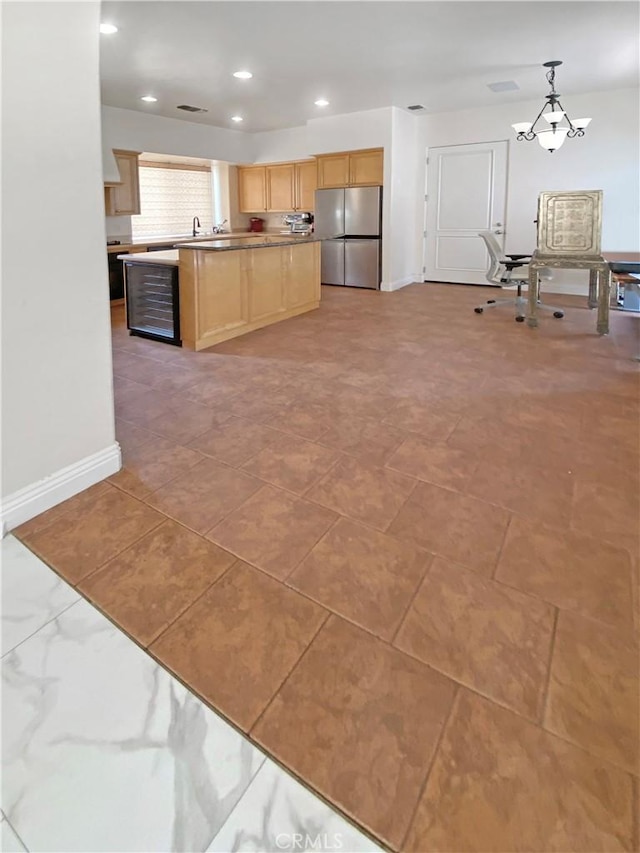 kitchen with baseboards, freestanding refrigerator, hanging light fixtures, light countertops, and light brown cabinetry