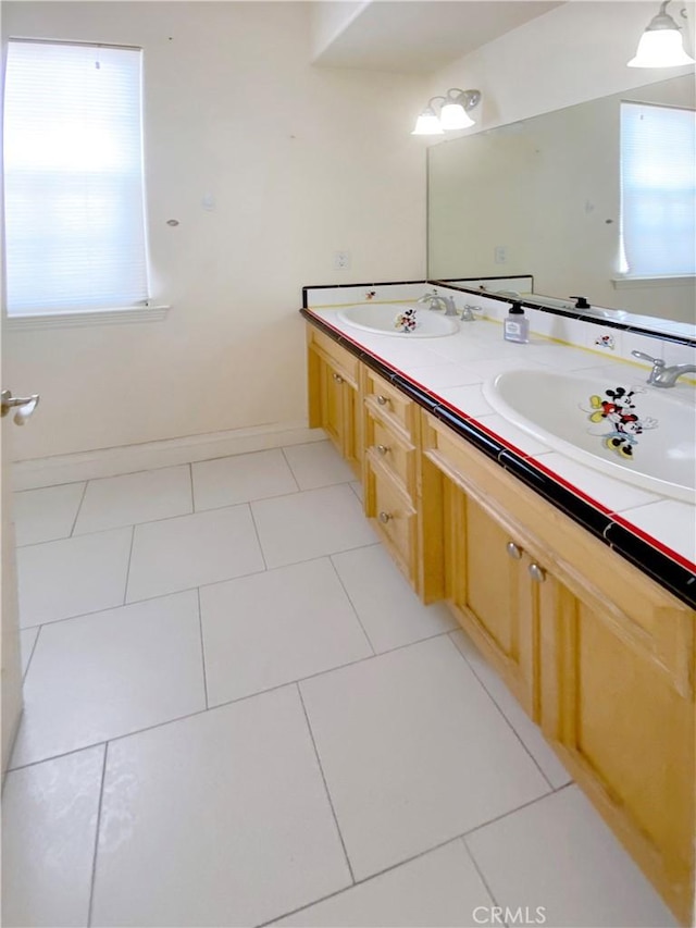 full bath featuring double vanity, a sink, baseboards, and tile patterned floors