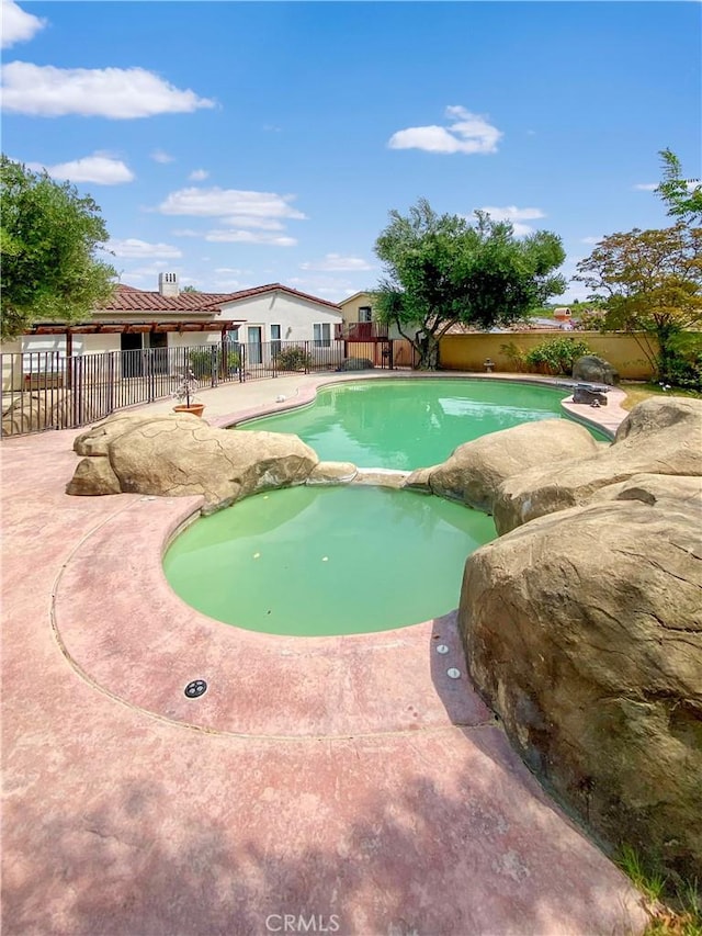 view of swimming pool featuring a patio, fence, and a pool with connected hot tub