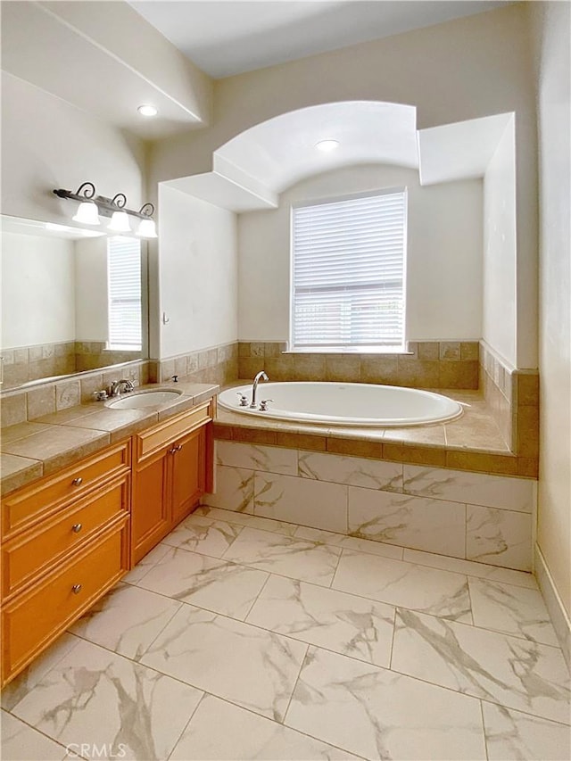 full bathroom with marble finish floor, vanity, and a bath