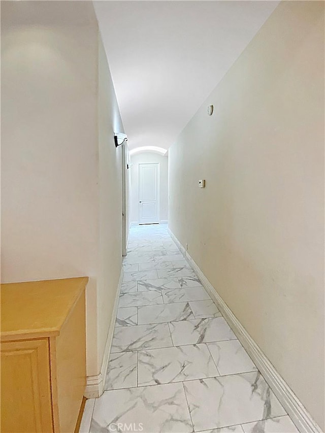 corridor with marble finish floor and baseboards