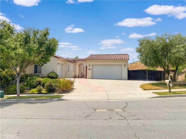 view of front of property featuring a garage, concrete driveway, a tiled roof, fence, and stucco siding