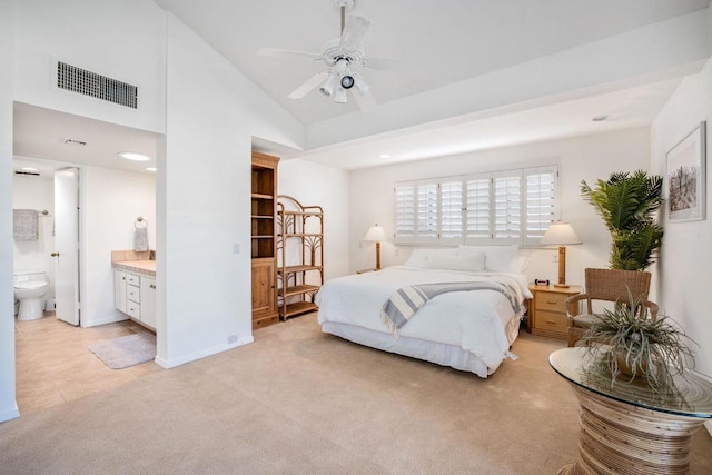 bedroom featuring light carpet, connected bathroom, vaulted ceiling, and ceiling fan