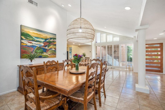 tiled dining room with decorative columns and high vaulted ceiling