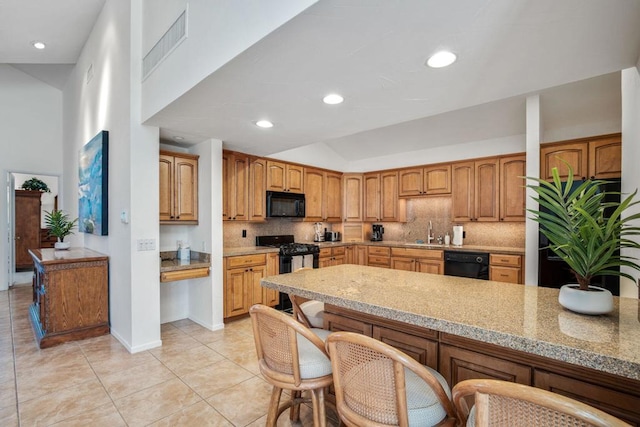 kitchen with sink, a high ceiling, backsplash, light tile patterned flooring, and black appliances