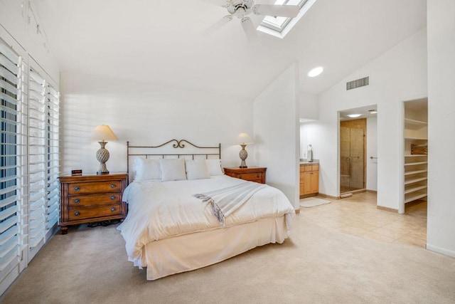 carpeted bedroom with ensuite bathroom, ceiling fan, high vaulted ceiling, and a skylight