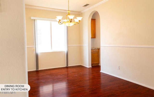 empty room featuring a chandelier, crown molding, and dark wood-type flooring