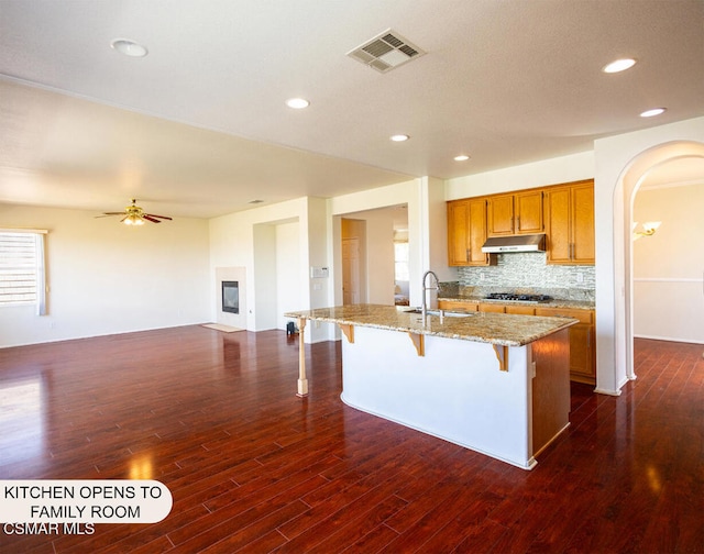 kitchen featuring a kitchen island with sink, ceiling fan, sink, dark hardwood / wood-style floors, and a breakfast bar area