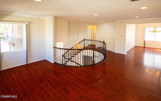 spare room featuring wood-type flooring, crown molding, and a chandelier