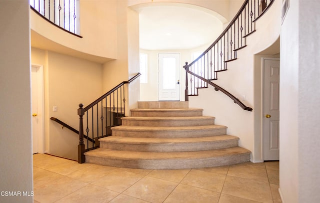 staircase with tile patterned flooring and a high ceiling