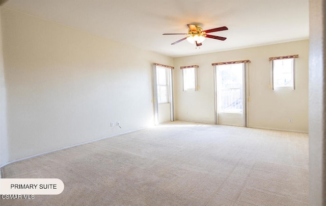 carpeted empty room with a wealth of natural light and ceiling fan