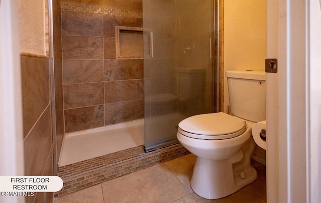 bathroom featuring toilet, tile patterned floors, and a shower with shower door