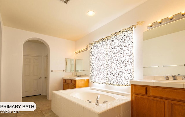 bathroom with tile patterned floors, vanity, and a relaxing tiled tub