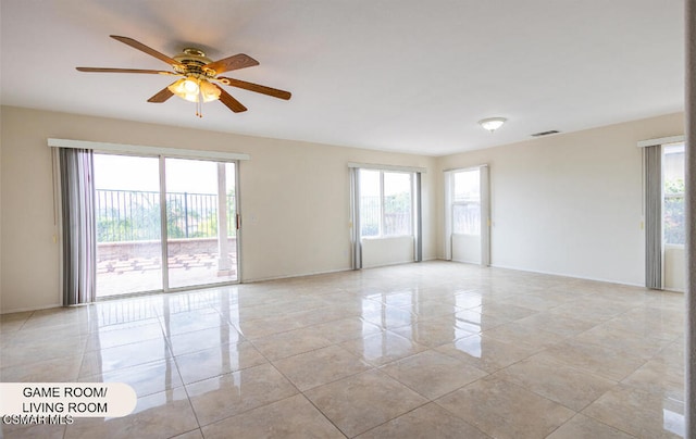 tiled spare room featuring ceiling fan and a healthy amount of sunlight