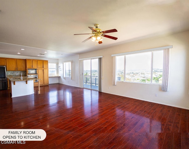 unfurnished living room featuring ceiling fan and dark wood-type flooring