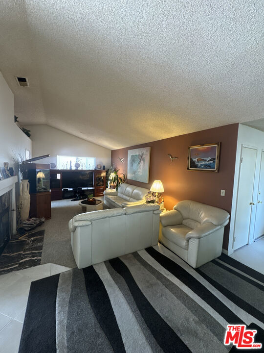 living room featuring a textured ceiling, light colored carpet, and lofted ceiling