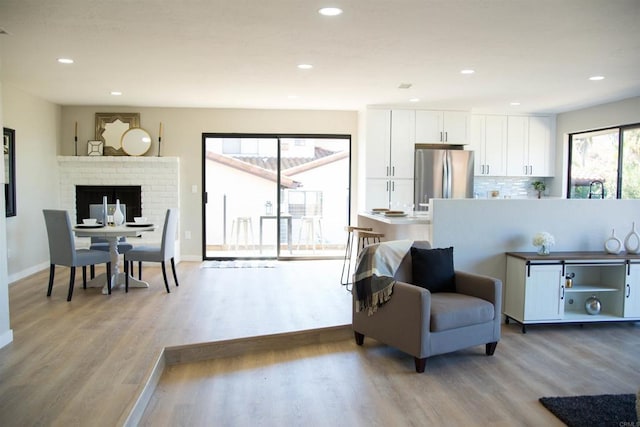 living room with a fireplace, light hardwood / wood-style flooring, and a wealth of natural light